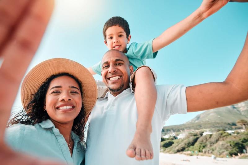 Happy family, smile and selfie at beach for summer with child, mother and father for fun.